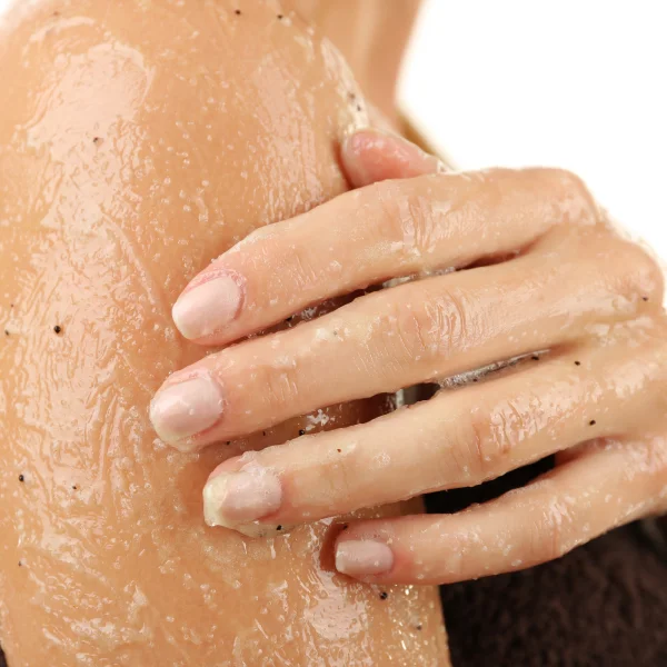 Une femme avec beaucoup de terre sur le bras, illustrant l'utilisation d'un exfoliant pour le corps.