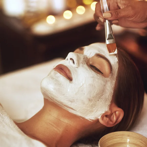 Une femme reçoit un soin du visage avec un masque, mettant en avant le meilleur soin à Montréal.