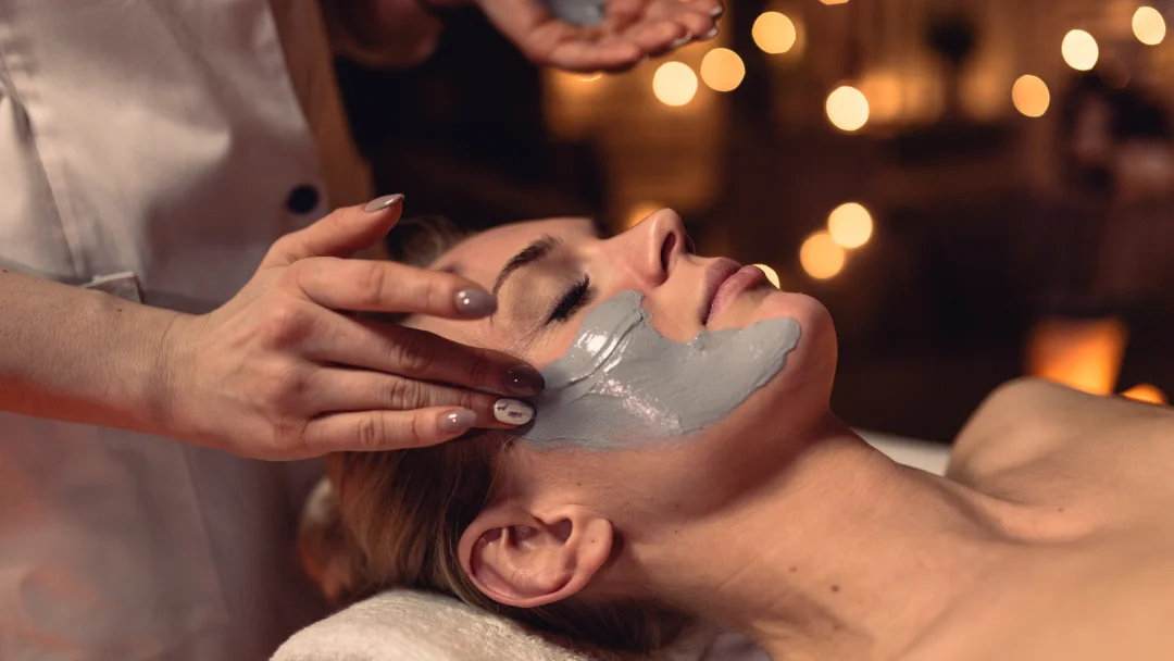 Une femme reçoit un masque facial dans un spa, mettant en avant le meilleur soin du visage à Montréal.