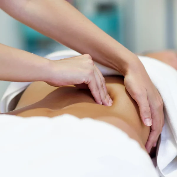 Une femme reçoit un massage lymphatique dans un spa, allongée sur une table de massage, entourée d'une ambiance relaxante.