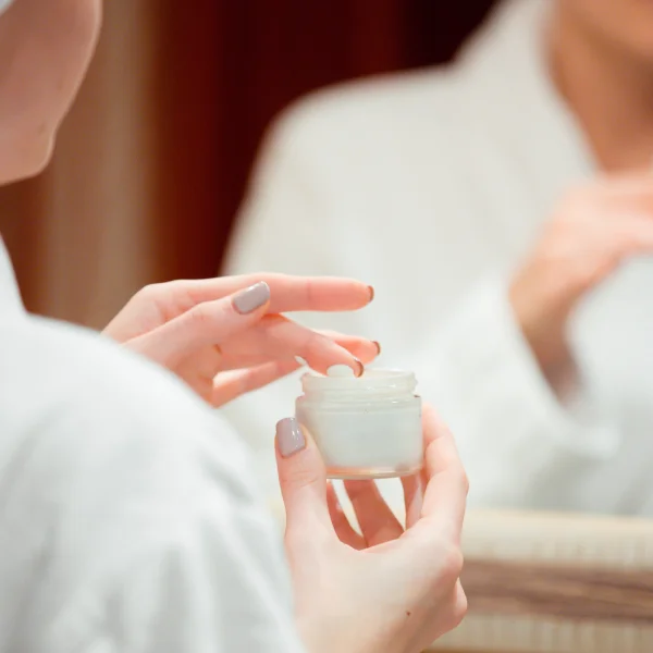 Femme en robe blanche, montrant les résultats d'une séance de microneedling avant/après.